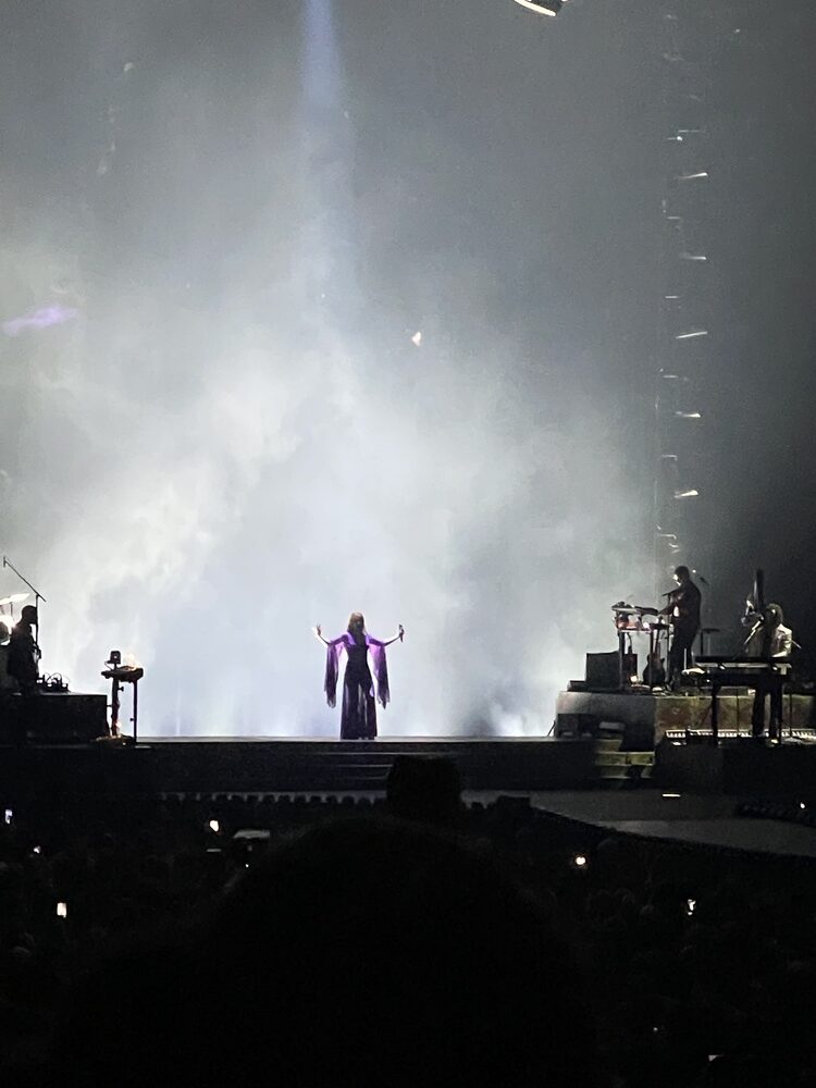 Florence Welch crossing onto a darkened stage as a Florence + the Machine concert begins